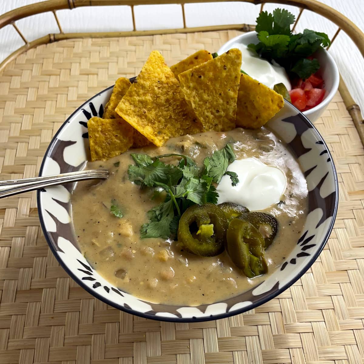 Bowl of white chicken chili topped with sour cream, jalapeños and cilantro